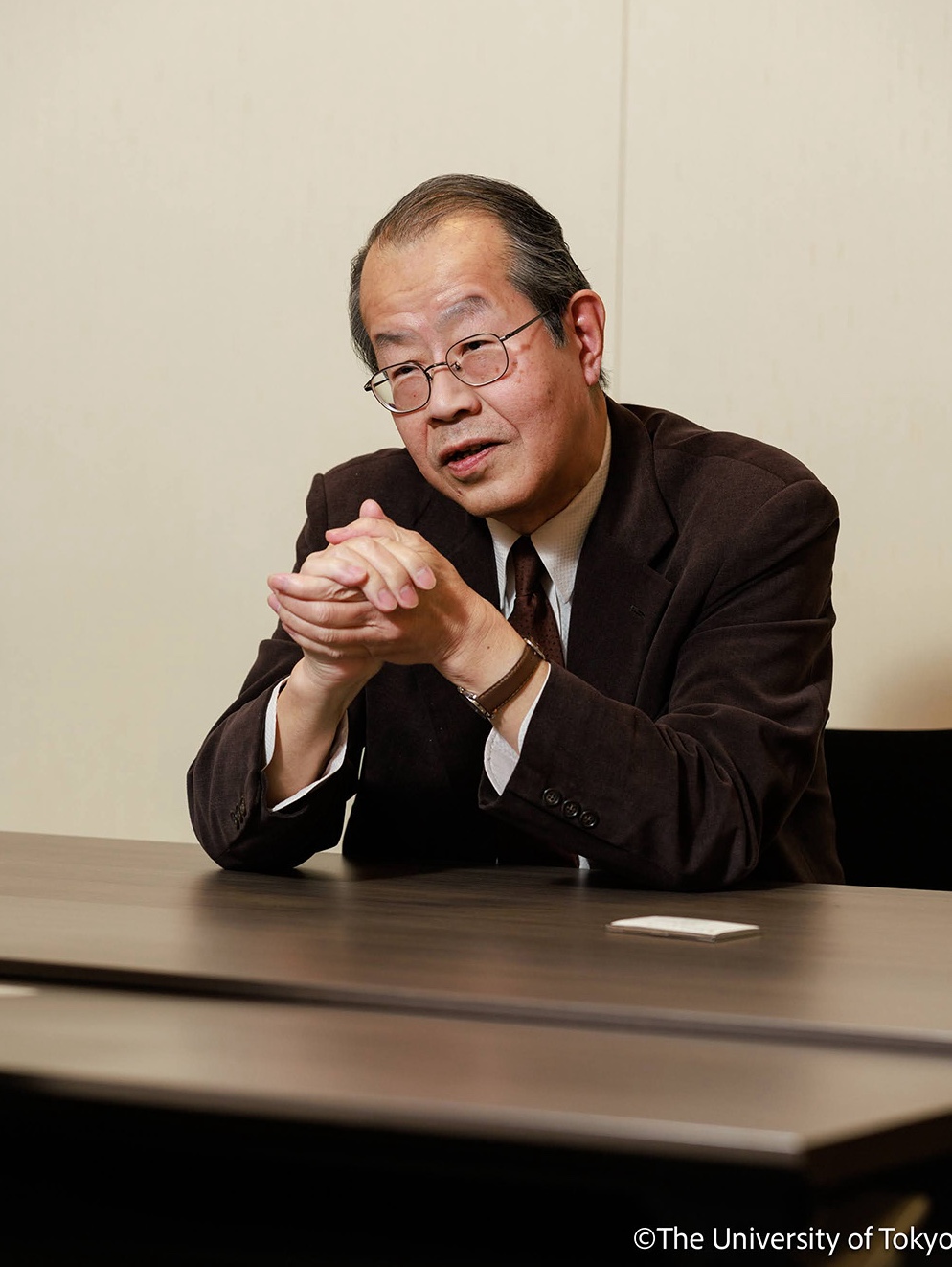 Portrait photo of Professor Yutaka Michida, sitting indoors at a table talking to someone out of view.