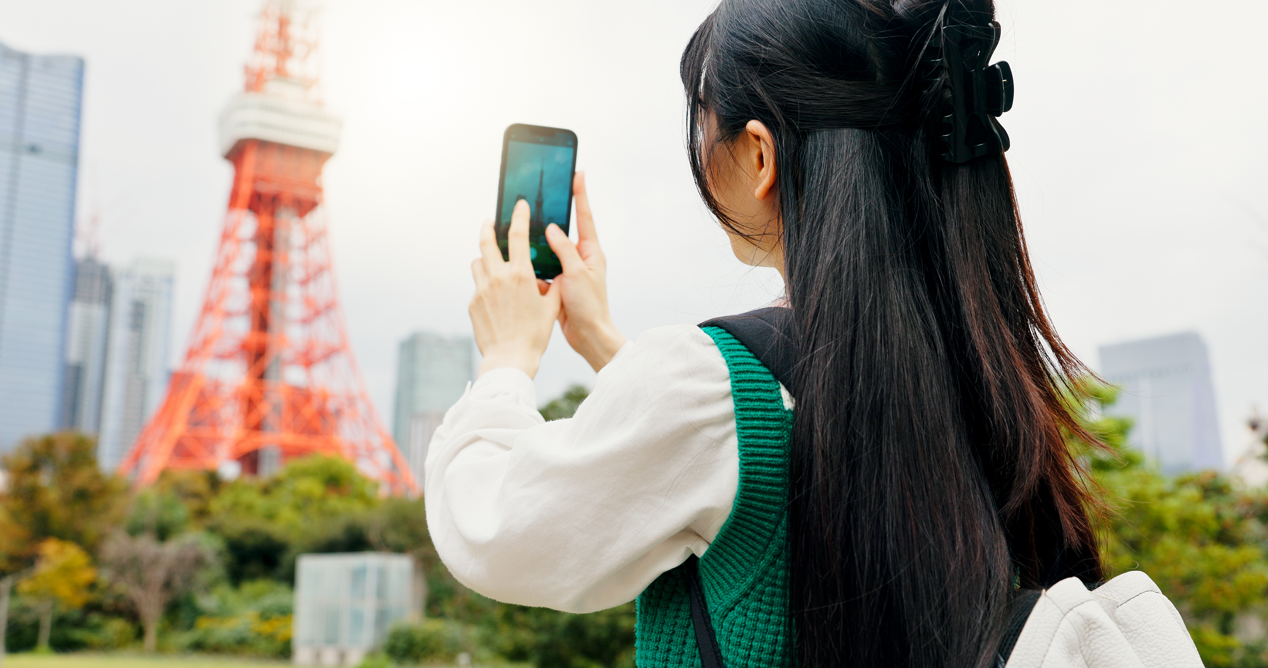 A woman taking a photo of Tokyo Tower with a smartphone