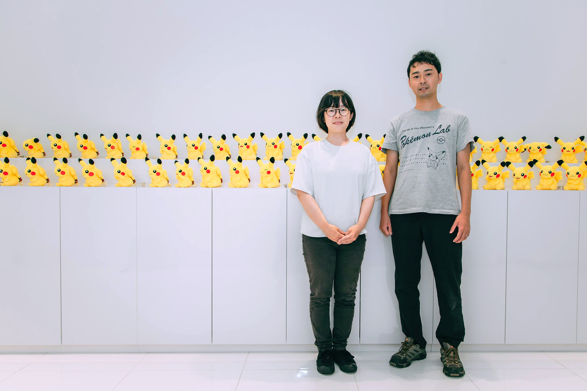 きのしたちひろさんと米原善成さんがたくさんのピカチュウのぬいぐるみの前で並んでいる写真